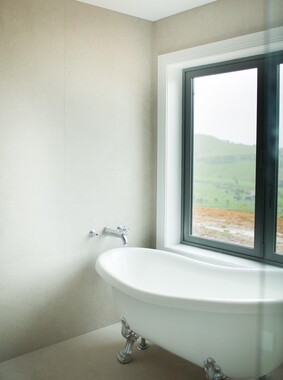 Photo of a modern bathroom with a beige painted wall and a white bathtub